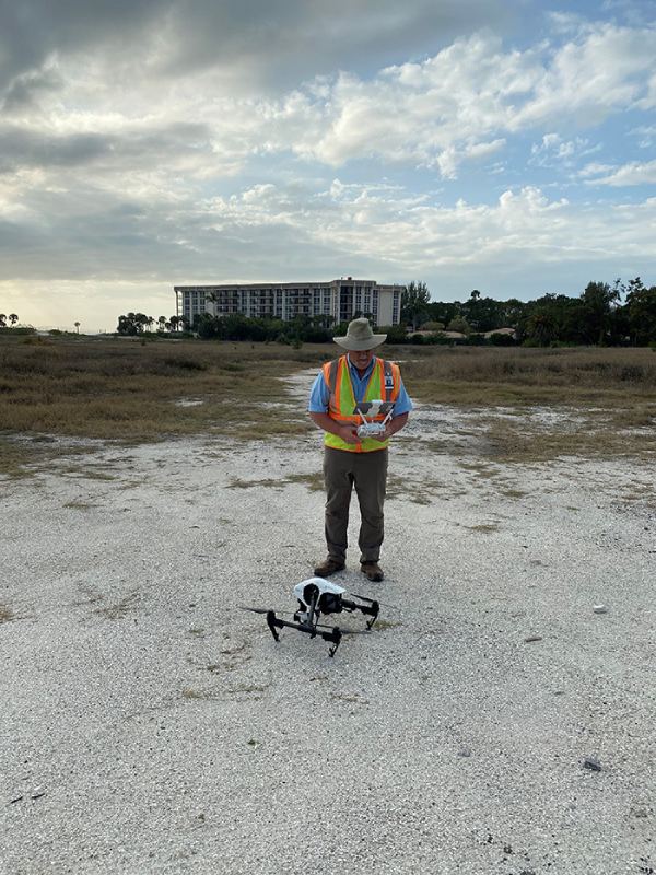 A Seismic Surveys technician is preparing a drone on the ground for a pre-construction survey.