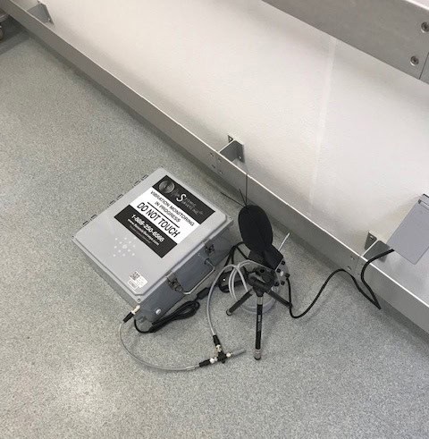 Noise and vibration monitoring equipment with a sound level microphone setup on an indoor floor