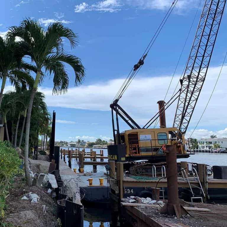 Pile driving crane and barge at a seawall monitored for marine construction vibration